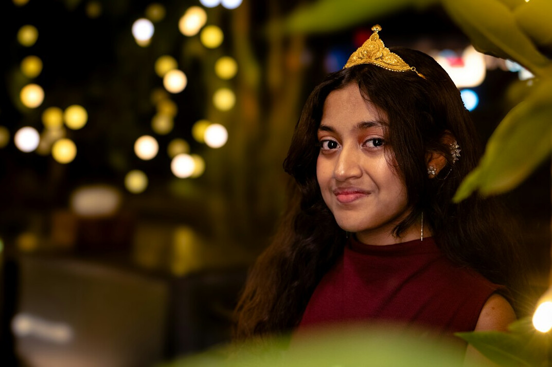 Singaporean teenage girl smiling while coding on a laptop